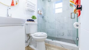 Un baño moderno con inodoro, lavamanos y ducha envuelta en vidrio.