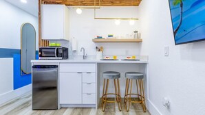 Una cocina compacta equipada con microondas, lavavajillas y dos taburetes.