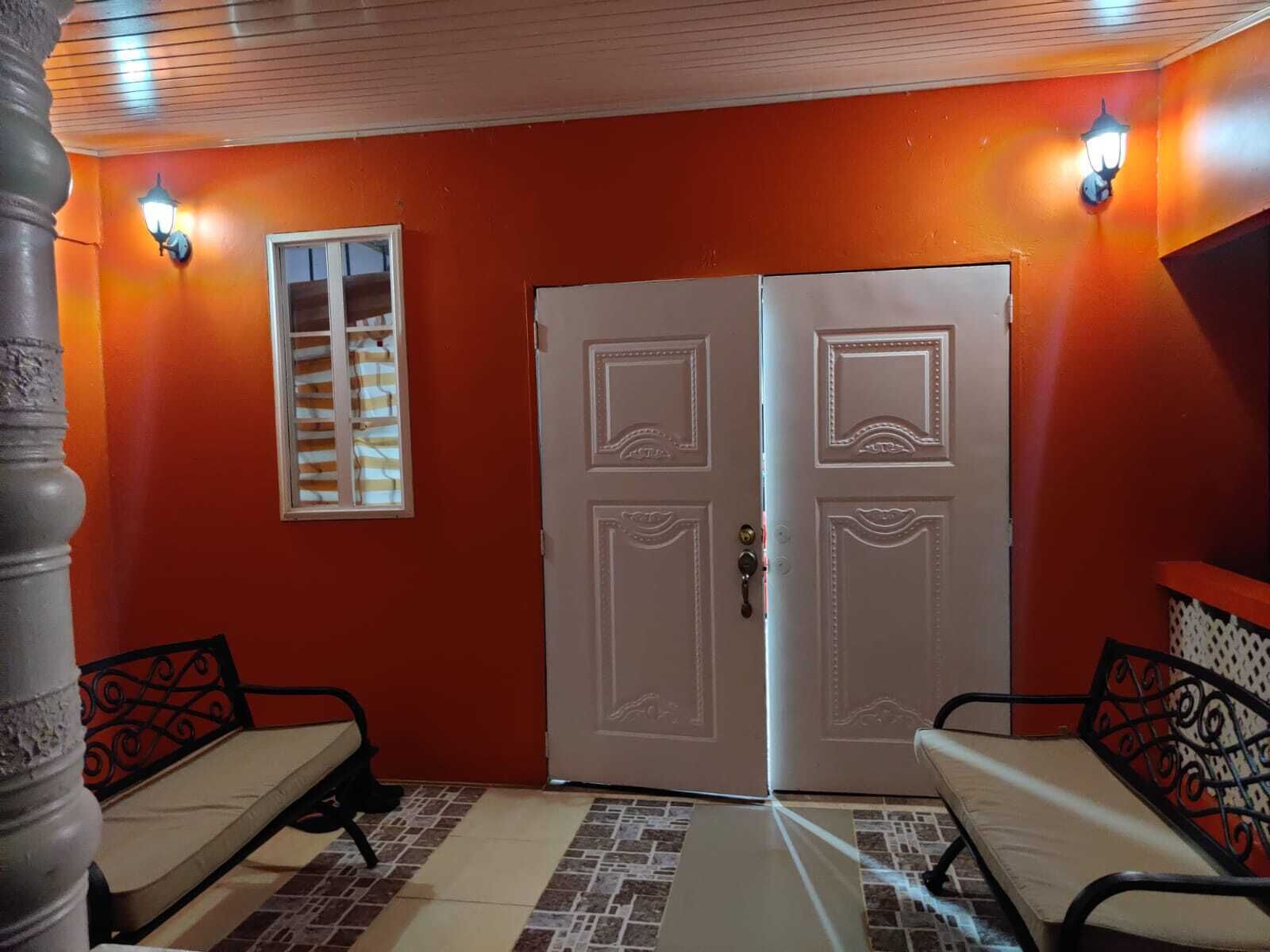 Una stanza con una parete rossa, una porta bianca e due sedie con struttura in metallo nero.