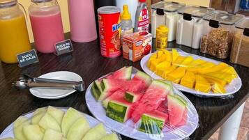 A breakfast buffet with various fruits, juices, and condiments.
