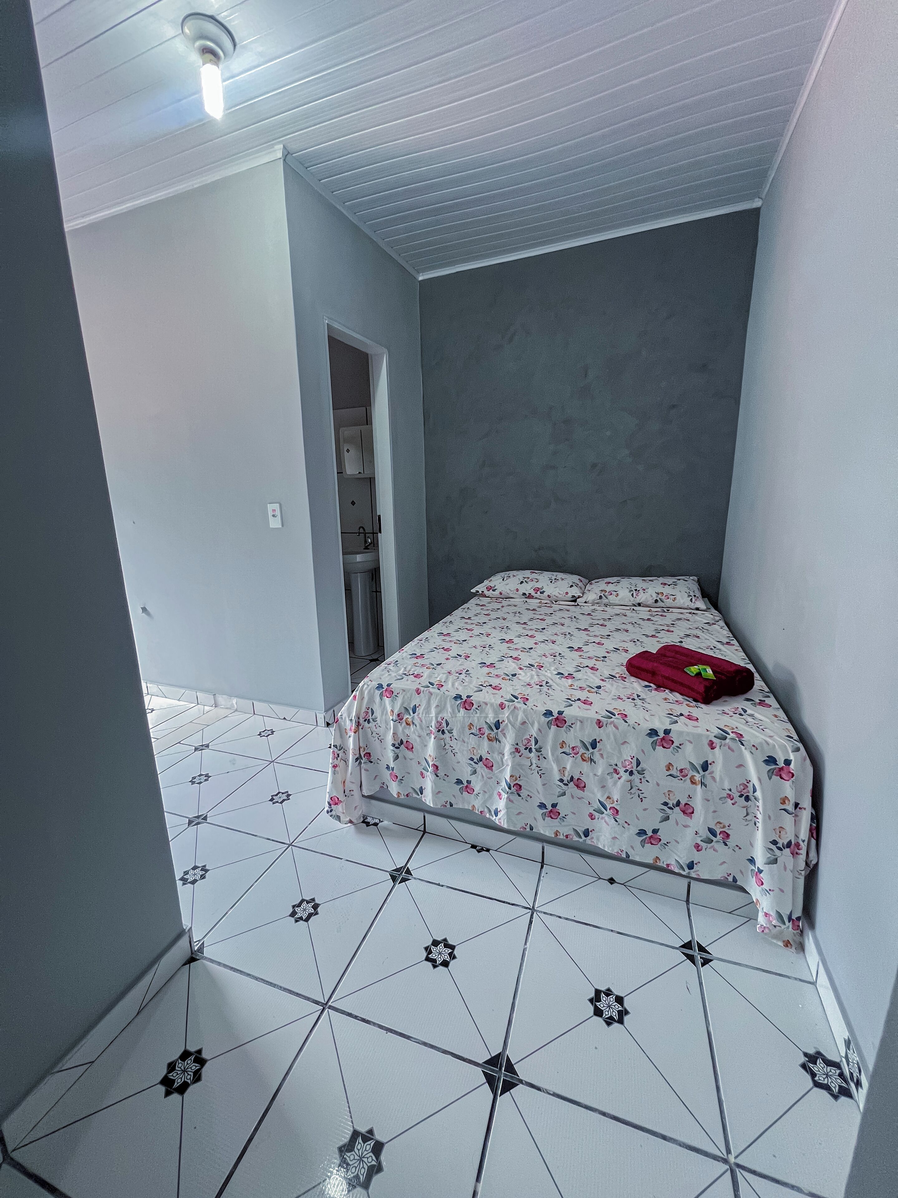 Un dormitori amb un llit, una taula de nit i una porta que condueix a un bany.