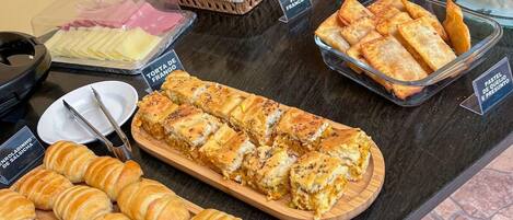 A buffet with various food items including croissants, pastries, and rice.