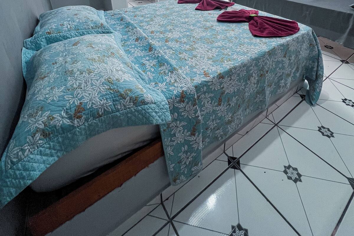A bedroom with a bed, a bench, and a small table.