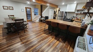 A spacious kitchen with wooden flooring, a central island with bar stools, a refrigerator, and a sink. - Beautiful mountainside hobby farm with gorgeous view! (Jasper)