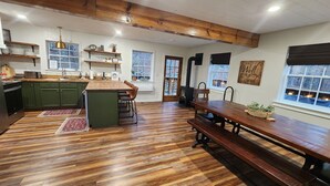 A spacious kitchen with wooden floors, a central island, and a dining area with a bench. - Beautiful mountainside hobby farm with gorgeous view! (Jasper)