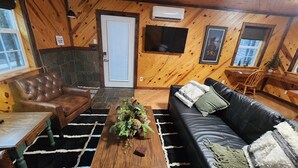 A cozy cabin interior with a stone fireplace, leather armchair, and a black leather sofa. - Beautiful mountainside hobby farm with gorgeous view! (Jasper)