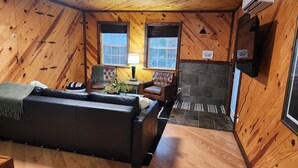 A cozy cabin interior with a wooden interior, a fireplace, a sofa, two chairs, and a lamp. - Beautiful mountainside hobby farm with gorgeous view! (Jasper)