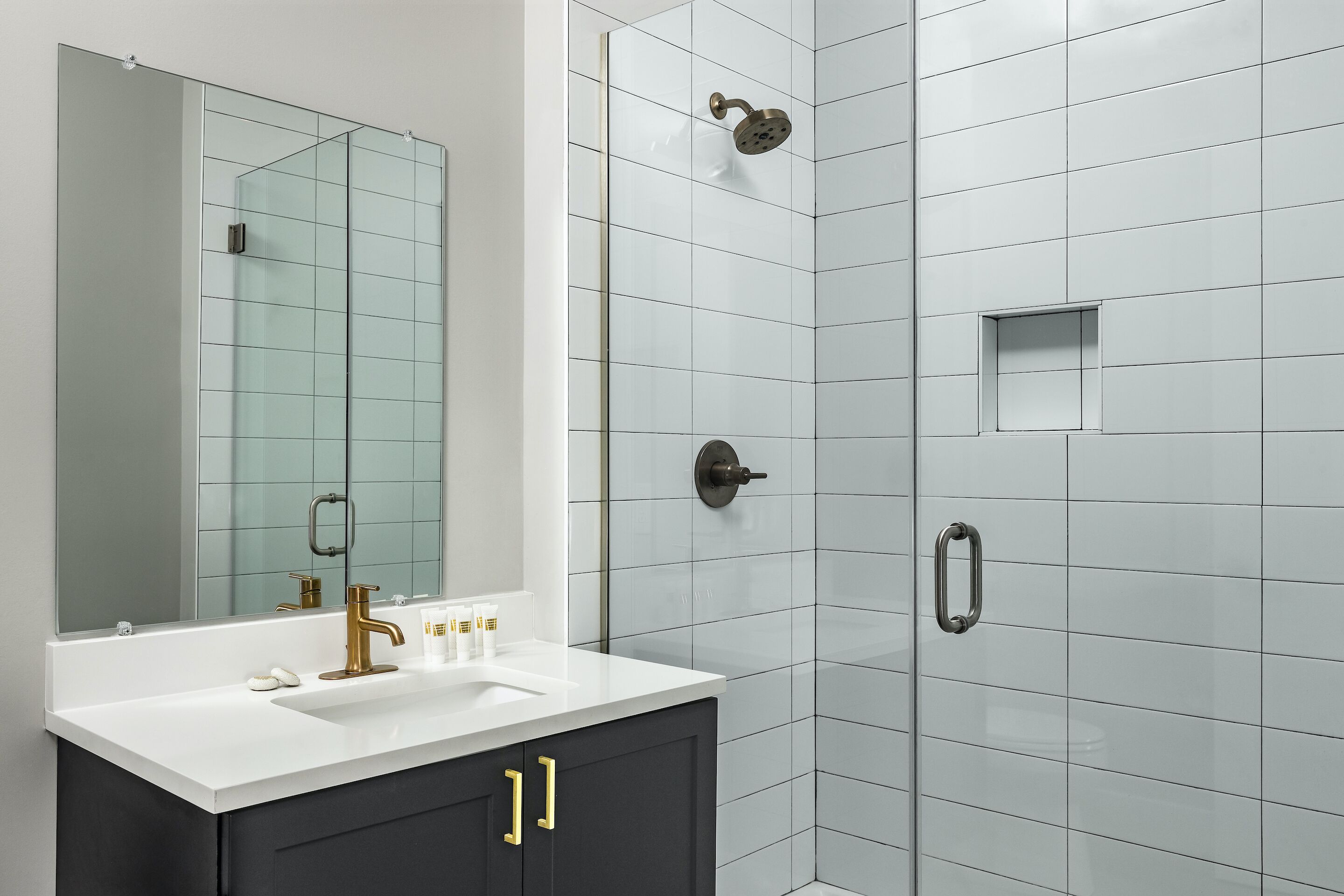 Une salle de bain moderne avec un lavabo blanc, un robinet doré et des meubles sombres.