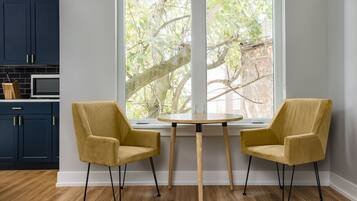 A modern kitchen with dark blue cabinets, a wooden table, and two mustard-colored chairs.