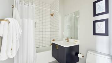 Une salle de bain moderne avec une baignoire, un grand miroir et des toilettes.