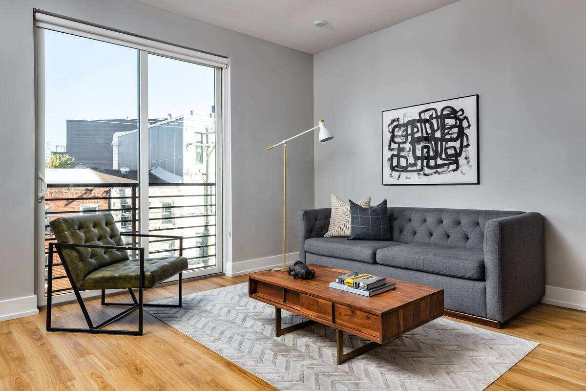 A modern living room with a grey sofa, a green armchair, and a wooden coffee table.
