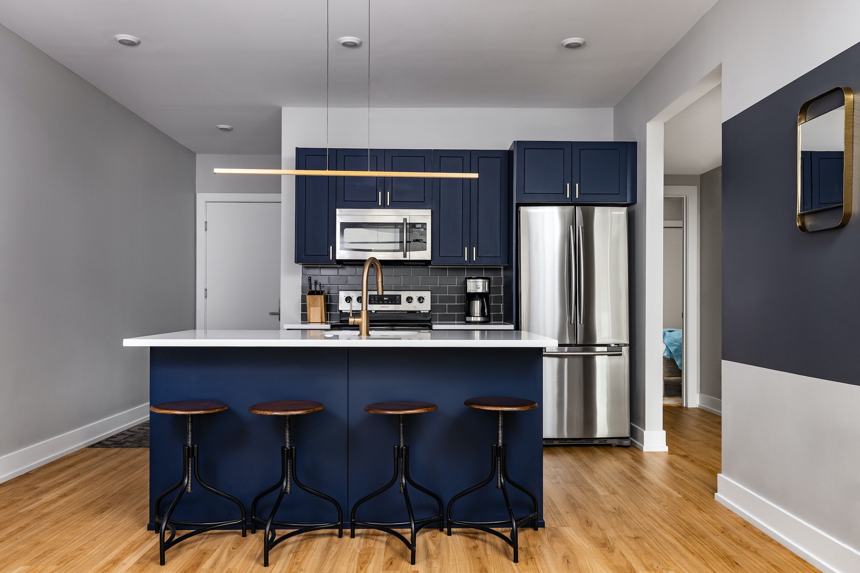 A modern kitchen with dark blue cabinets, stainless steel appliances, and a bar area with stools.