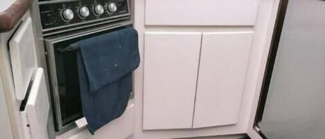 A kitchen with a stove, oven, and cabinets. There is a round rug with a sea turtle design on the floor.