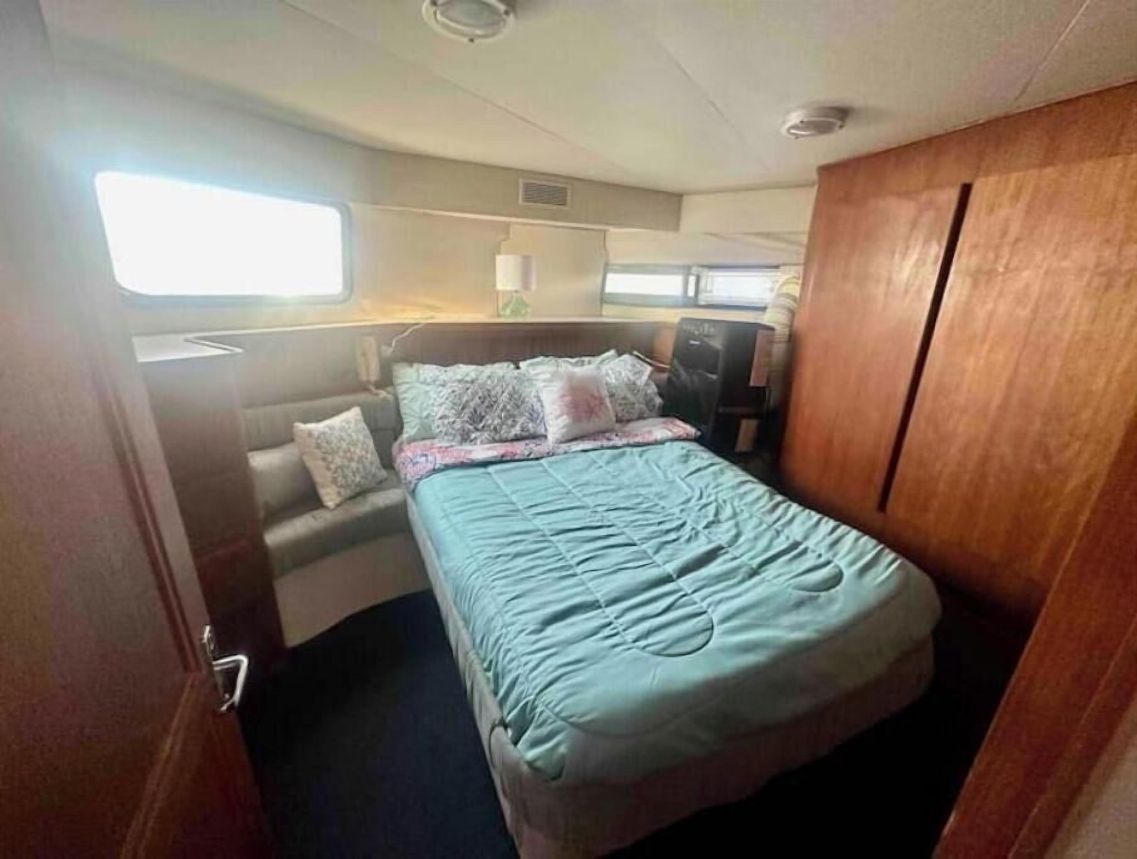 A compact bedroom with a bed, a small seating area, and a window.