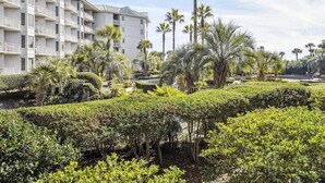 A hotel with multiple floors, balconies, and a well-maintained garden with various plants and trees. - MyStay at 1102 Sea Crest - Sea Crest Resort Oceanfront Complex | Steps to Beach (Hilton Head Island)