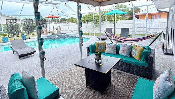 Un patio exterior con piscina, zonas de estar y un ventilador de techo.