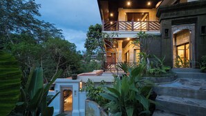 A two-story building with a balcony, surrounded by lush greenery and stone steps leading to the entrance. - Villa Celagi (Ubud)
