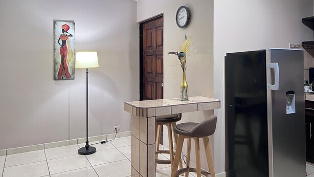 A kitchen with a refrigerator, a clock, a vase with flowers, and a painting on the wall. - Casa Florencia Liberia (Liberia)