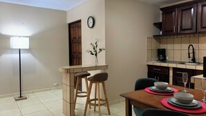 A dining area with a wooden table set for two, a vase with flowers, and a clock on the wall. - Casa Florencia Liberia (Liberia)