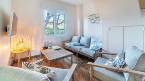 A cozy living room with a sofa, armchairs, a coffee table, and a TV mounted on the wall. - Le Rayolet Parc by Interhome (Six Fours)