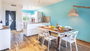 A modern kitchen with white cabinetry, a dining table with chairs, and a blue accent wall. - Le Rayolet Parc by Interhome (Six Fours)