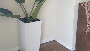 Una habitación de esquina con una planta blanca en maceta, un cuadro en la pared y una silla marrón.