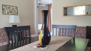 Un comedor con mesa, sillas, un jarrón y un sofá.