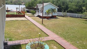 Un patio trasero con terraza de madera, una casa pequeña y un área cercada.
