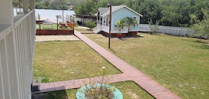 A backyard with a wooden deck, a small house, and a fenced area. - Charming 1-bedroom apartment with Starlink WiFi, AC, in lovely Calabash Bight (Islas de la Bahía)