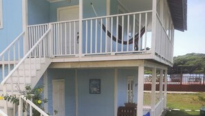 Una casa de dos pisos con balcón, puerta principal y un pequeño porche.