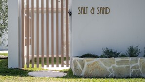 A gated entrance with a wooden fence and a wall with the text "SALT & SAND".