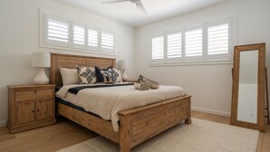 A bedroom with a wooden bed, two bedside tables, a ceiling fan, and a large mirror.