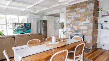 A modern kitchen with a stone wall, wooden dining table, and white cabinetry.
