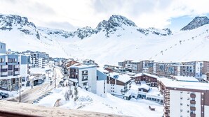 A snow-covered mountain town with modern buildings, a ski slope, and a clear sky.