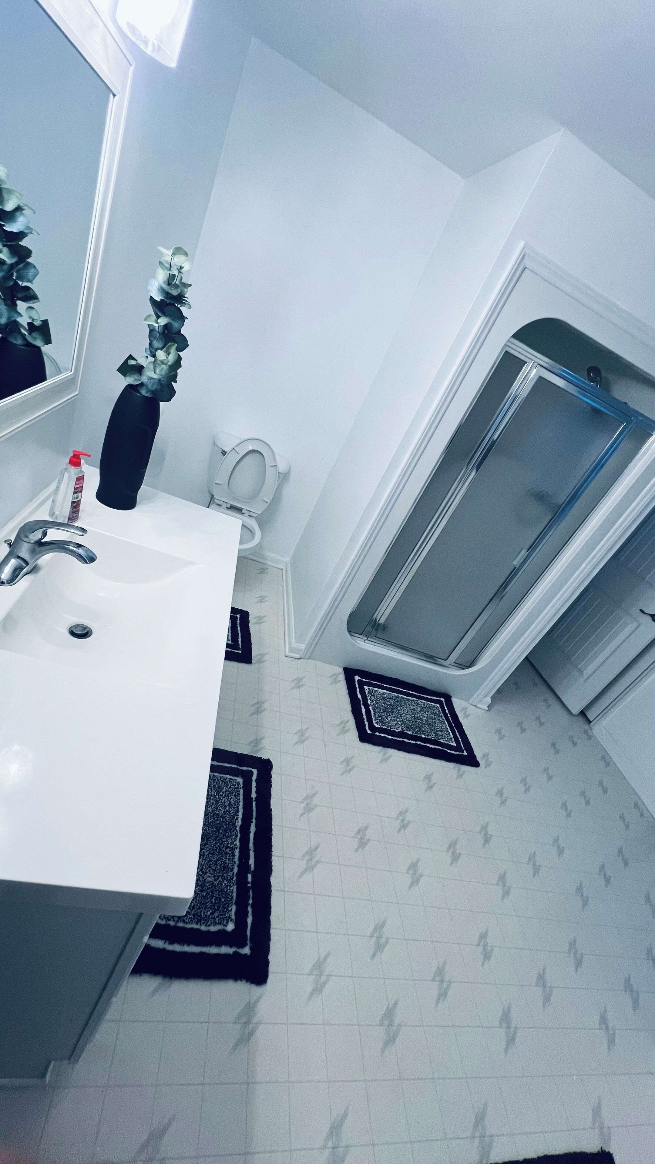 Un baño con un lavamanos blanco, un espejo, un inodoro y una zona de ducha.