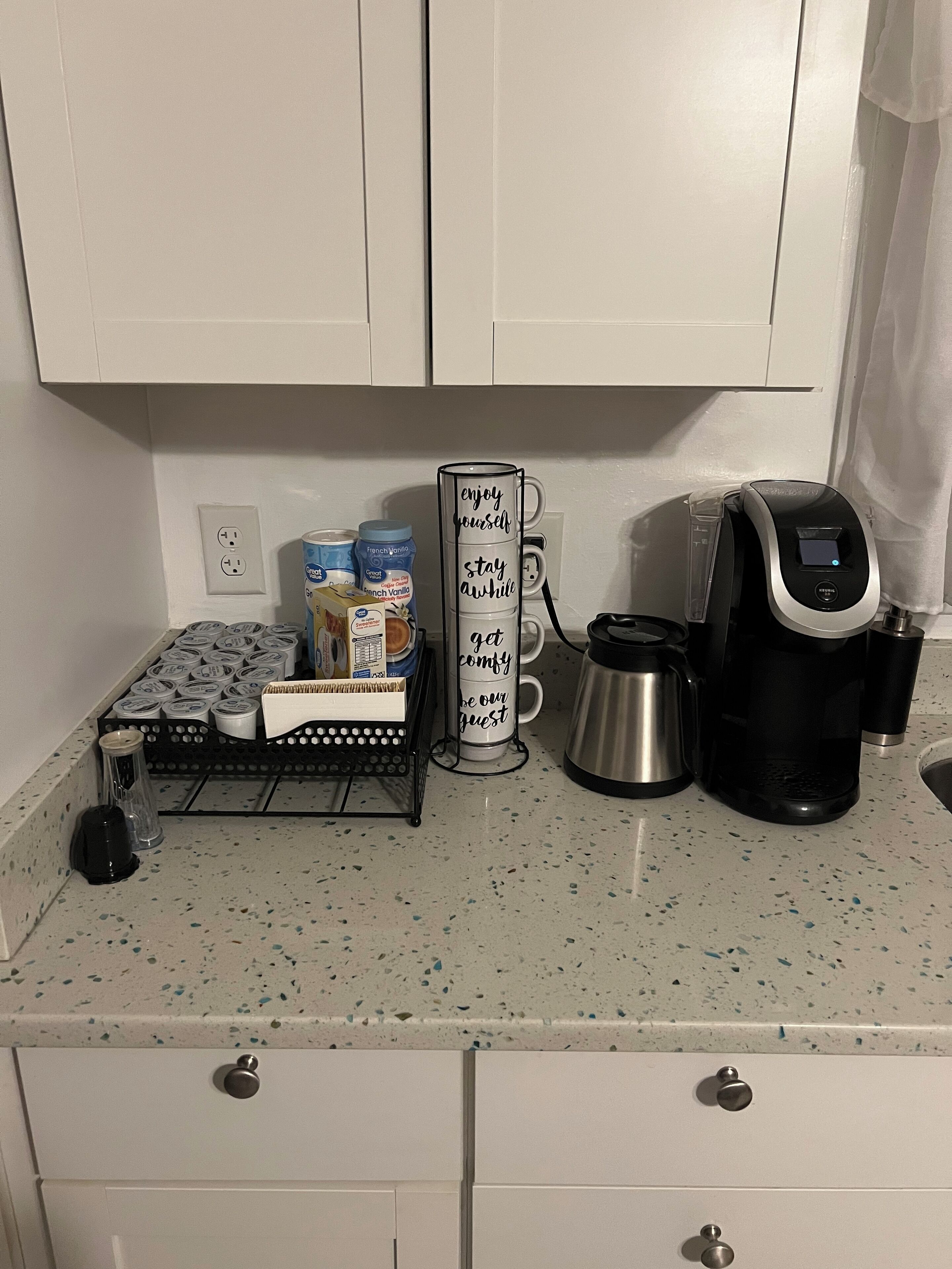 A kitchen counter with a coffee maker, a mug rack, and various kitchen items.