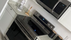 A modern kitchen with stainless steel appliances, a countertop with a blender, and a microwave. - Charming 3-bedroom house in beautiful Jacksonville With WiFI & workspace. (Jacksonville)