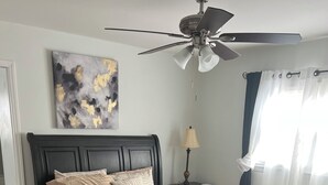 A neatly arranged bedroom with a bed, bedside table, lamp, and a ceiling fan. - Charming 3-bedroom house in beautiful Jacksonville With WiFI & workspace. (Jacksonville)