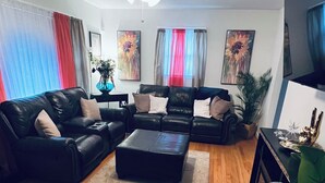 A living room with a black leather sofa set, a coffee table, and a ceiling fan. - Charming 3-bedroom house in beautiful Jacksonville With WiFI & workspace. (Jacksonville)