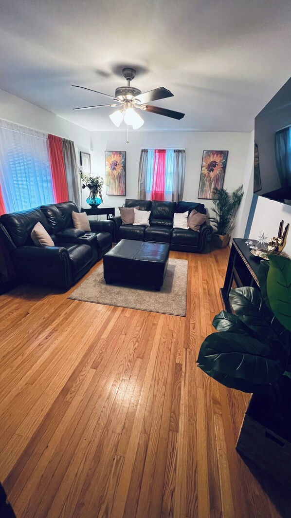 A living room with a black leather sofa set, a coffee table, and a ceiling fan.