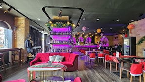 Eine Bar mit einer neonbeleuchteten Theke, roten Sitzgelegenheiten und einem Holzboden.