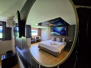 Een moderne hotelkamer met een groot bed, een flatscreen televisie aan de muur en een muurschildering van de ruimte.
