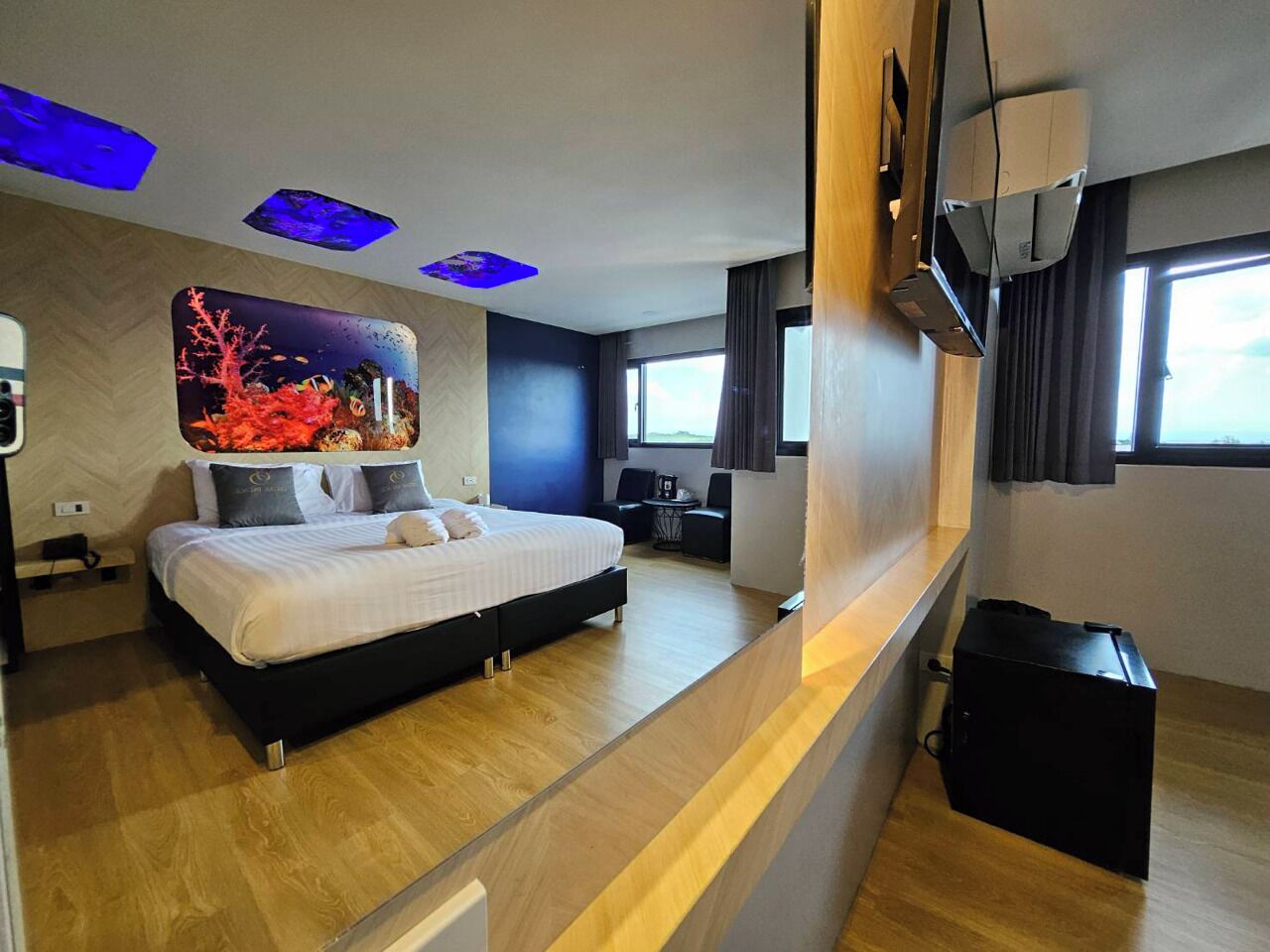 A modern hotel room with a bed, a desk, and a large window.