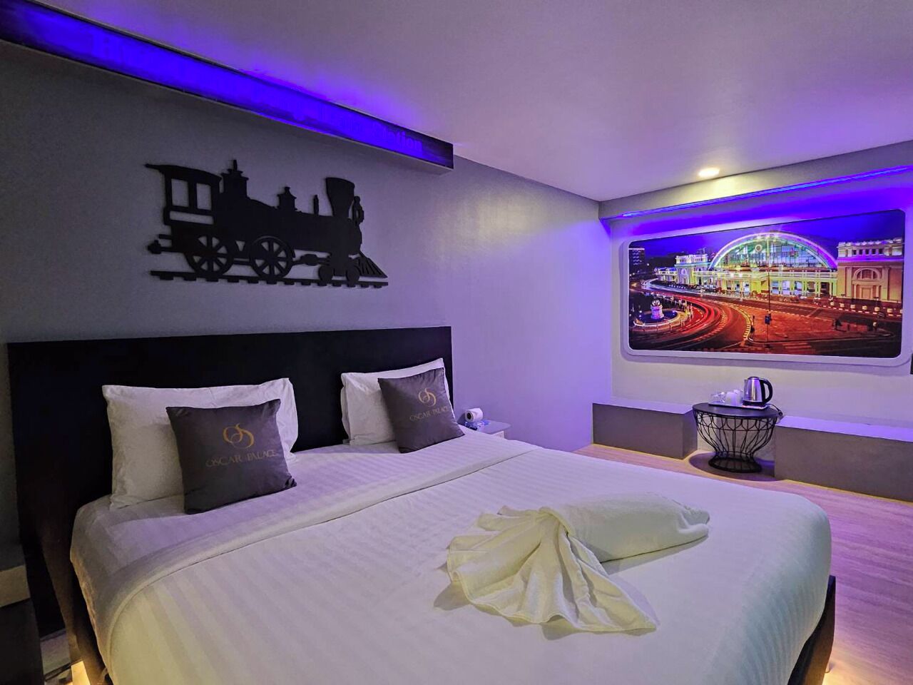Camera d'albergo con un letto, una testiera, un'opera d'arte a parete raffigurante un treno e una finestra con vista sulla città.