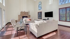 Un salón espacioso con chimenea, un televisor de pantalla plana y ventanas amplias.