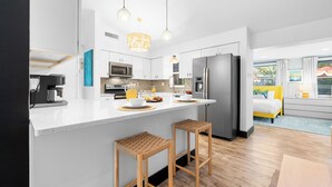 A modern kitchen with white cabinets, stainless steel appliances, and a central island with stools. - Beach Oasis: Hot tub, Pool, Mini-golf, Game Room (Seminole)