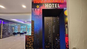 A hotel entrance with a neon sign reading "Hollywood Hotel" and a cityscape mural. - Hollywood Dannok Hotel (Sadao)
