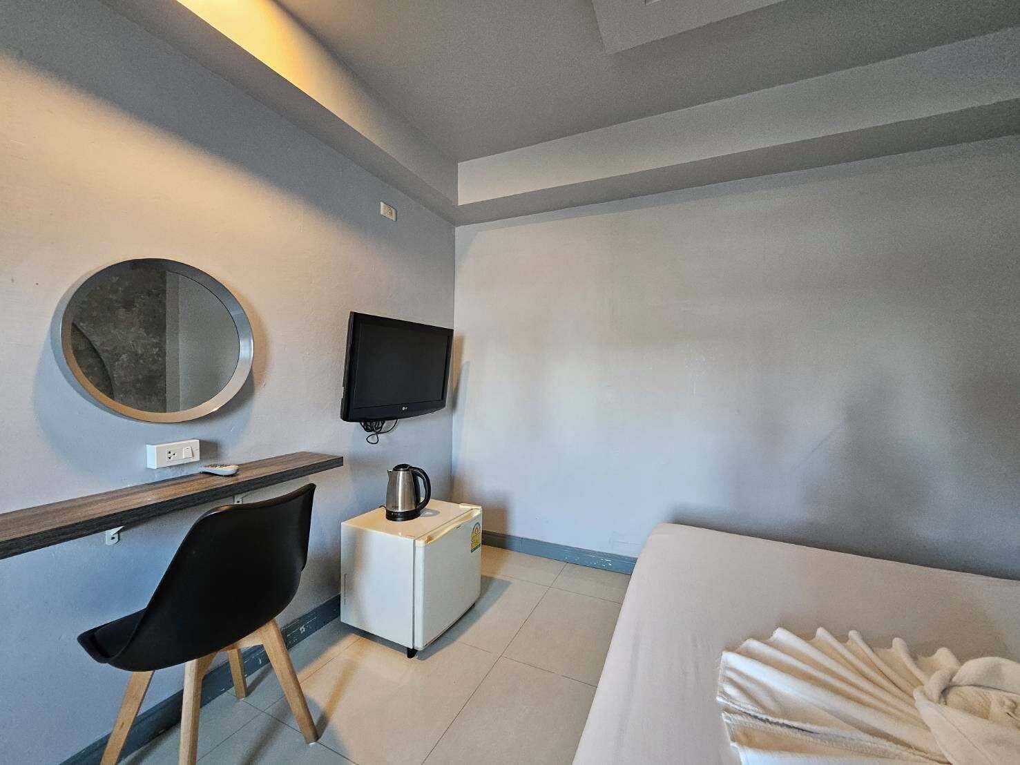 Une chambre d’hôtel comprenant un lit, un bureau avec une chaise, une télévision, une machine à café et un miroir.