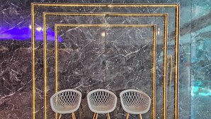 A room with a marble wall and three white chairs with wooden legs. - Hollywood Dannok Hotel (Sadao)