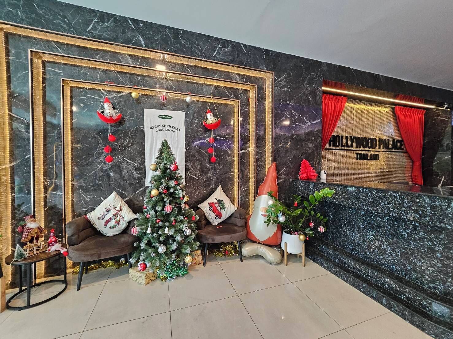 A lobby with a Christmas tree, framed artwork, and a sign for Hollywood Palace.